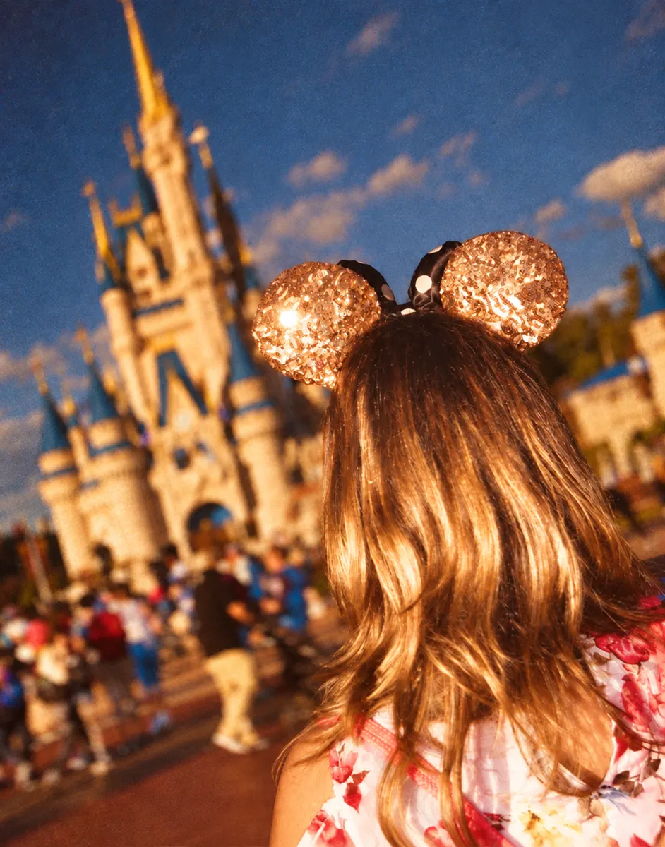 Pasajera con orejas de Minnie frente al castillo
