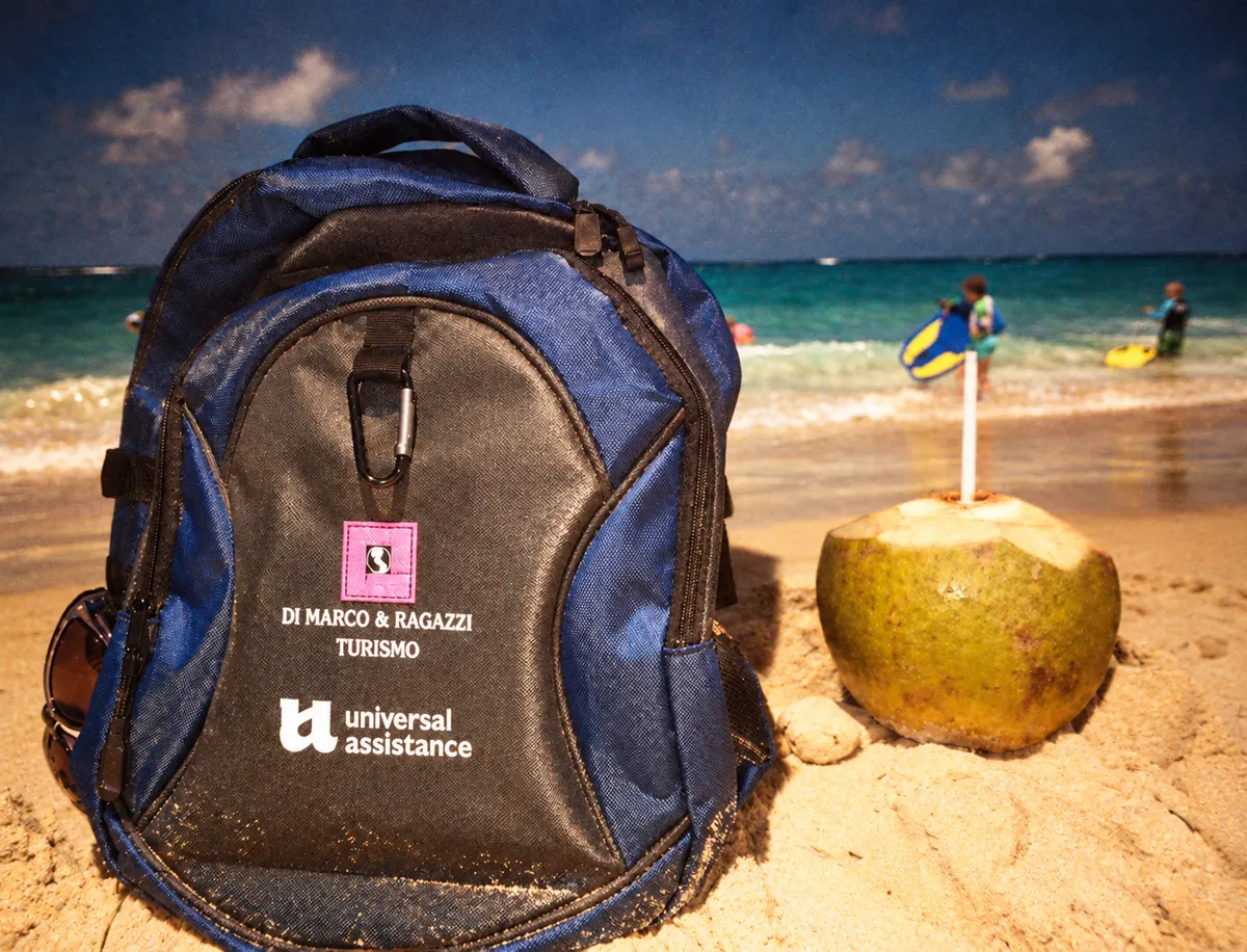 Mochila de la agencia en la playa junto a un coco